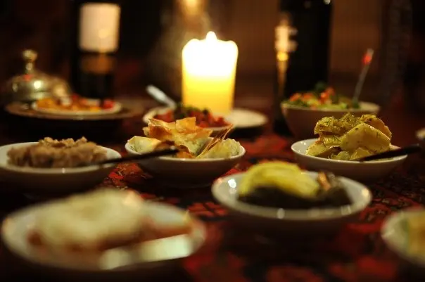 Candlelit table crowded with small meze plates